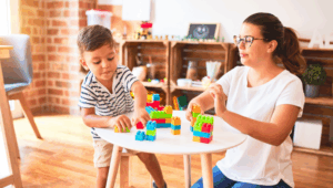 A daycare provider plays Legos with a young boy.