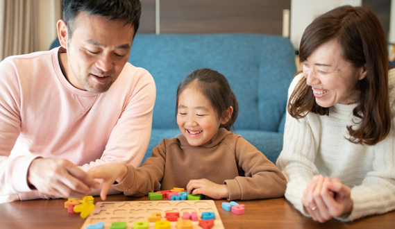 Parents and their daughter play with block letters.