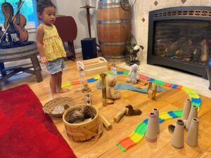 A young child stands in front of toys and activities on a living room floor.