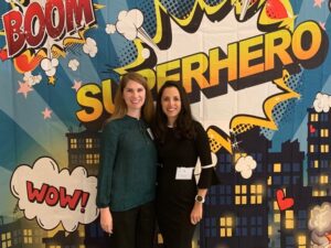 Executive Director Patricia Lozano and Senior Policy Advisor Stephanie Tseu pose in front of a Superhero banner.