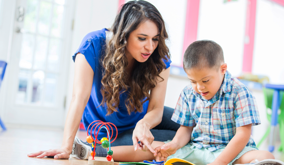 A teacher helps a child reading a book.