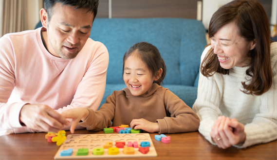 Asian parents play with letter blocks with their daughter.