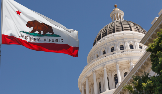 The Sacramento Capitol building with the California state flag in the foreground.