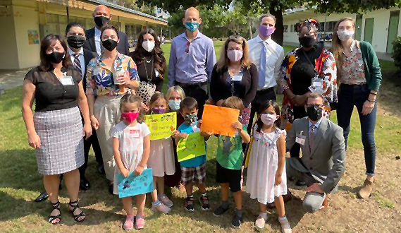 Policymakers pose outside a school for a picture with San Diego Unified students.