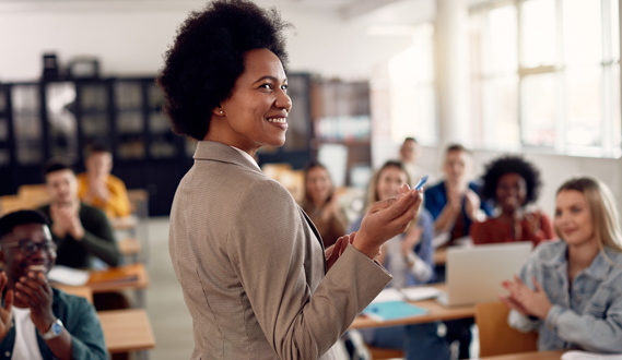 A professor smiles in front of her college students.