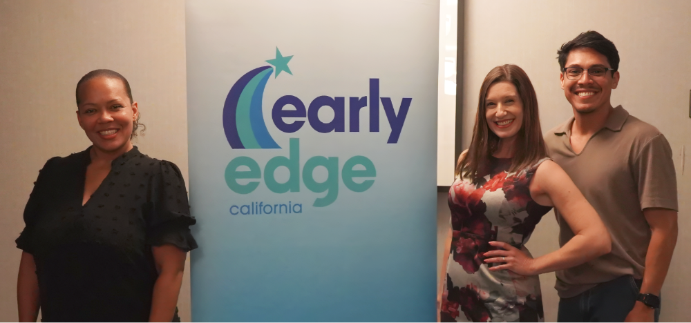 3 attendees pose in front of the Earl Edge banner