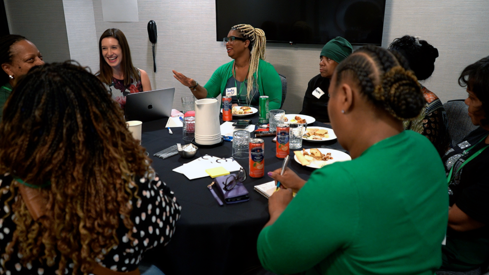 Attendees smile as one speaks.